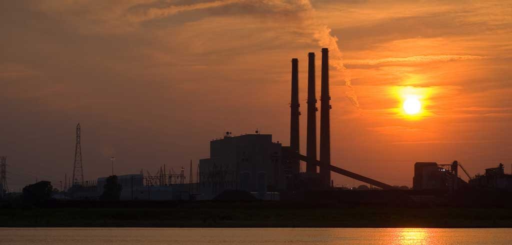 a coal power plant in an orange sky at sunset