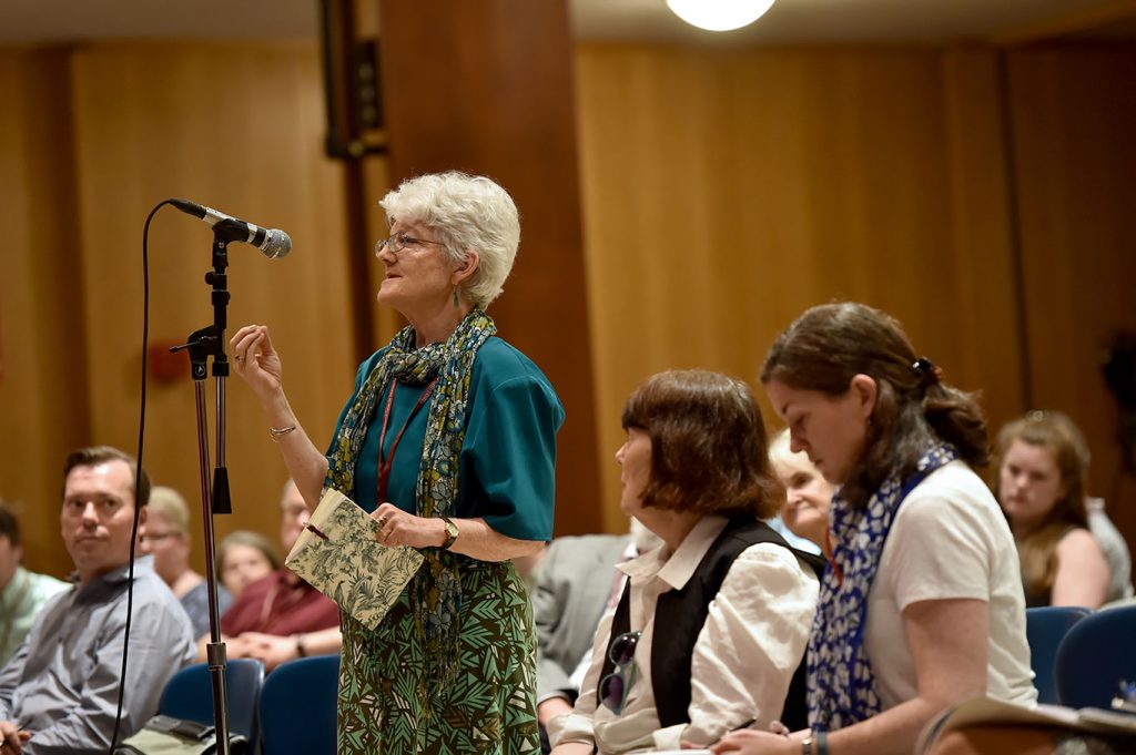 An attendee at the conference asks a question of the panelists from a microphone.