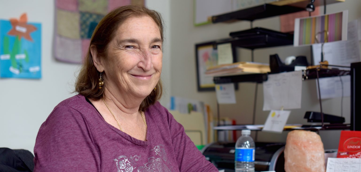 Marilyn Bisberg smiles at the camera in her office.