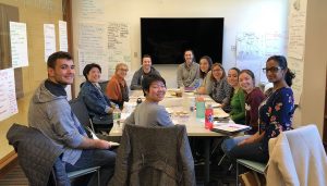 Members of the "Our Story" team of students seated around a table at the Rose Hill campus. 