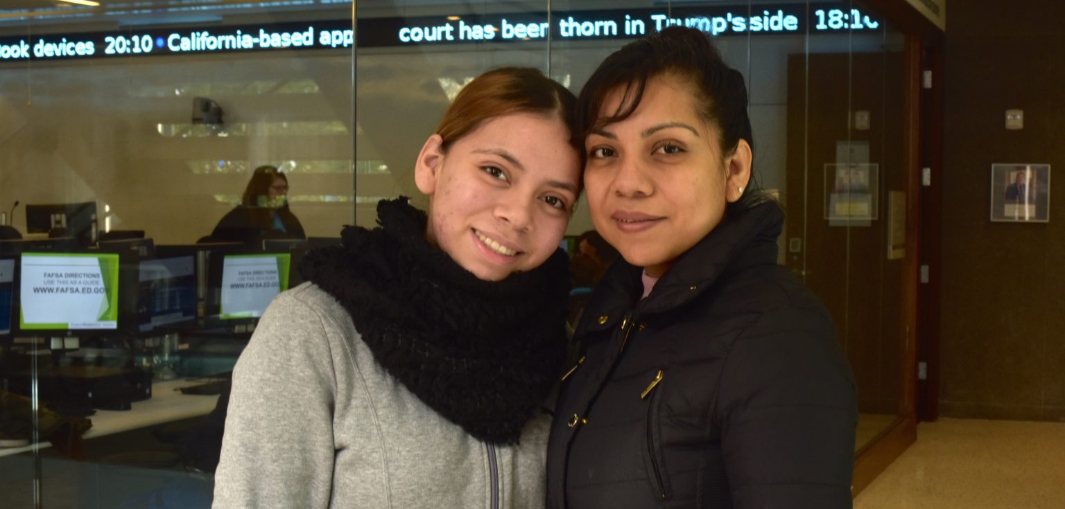 A woman and her daughter smile at the camera.