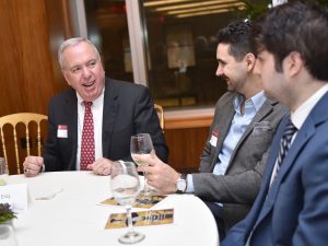  John J. Reddy Jr., Esq., FCRH ’76, PAR, speaks with two young men at a table.