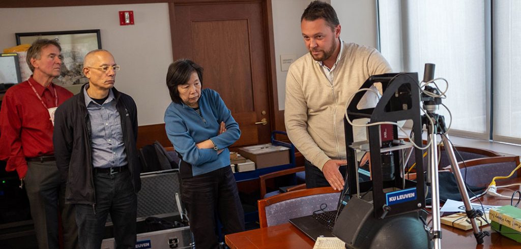 A man demonstrates a scanner to three members of the Fordham Libraries staff