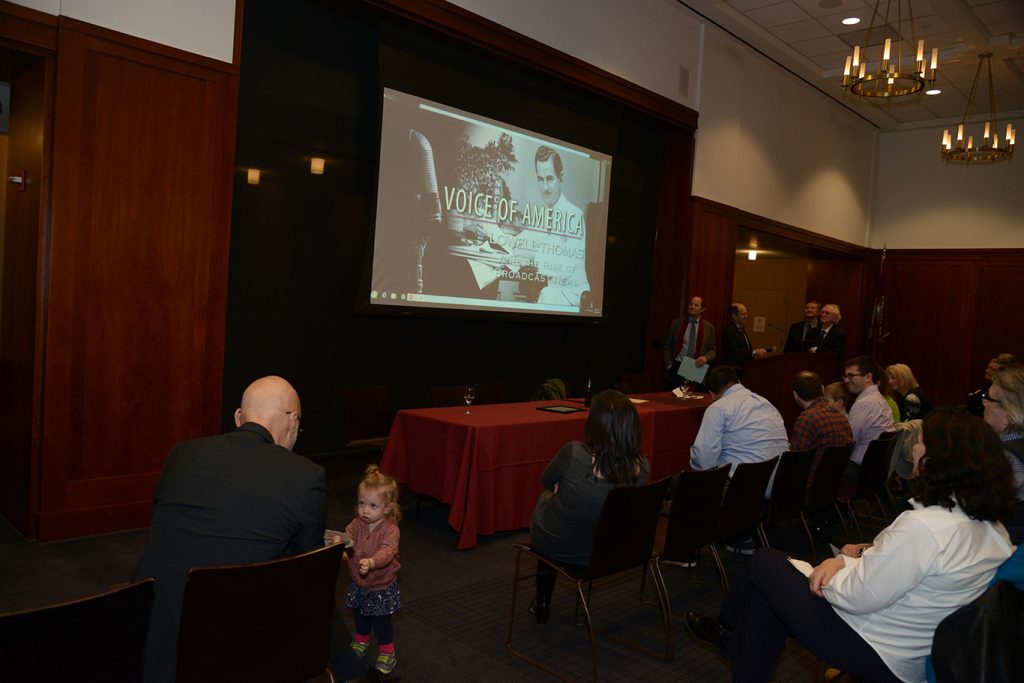 The audience at the 12th floor lounge watches a three minute clip of The Voice of America: Lowell Thomas and the Rise of Broadcast Journalism.