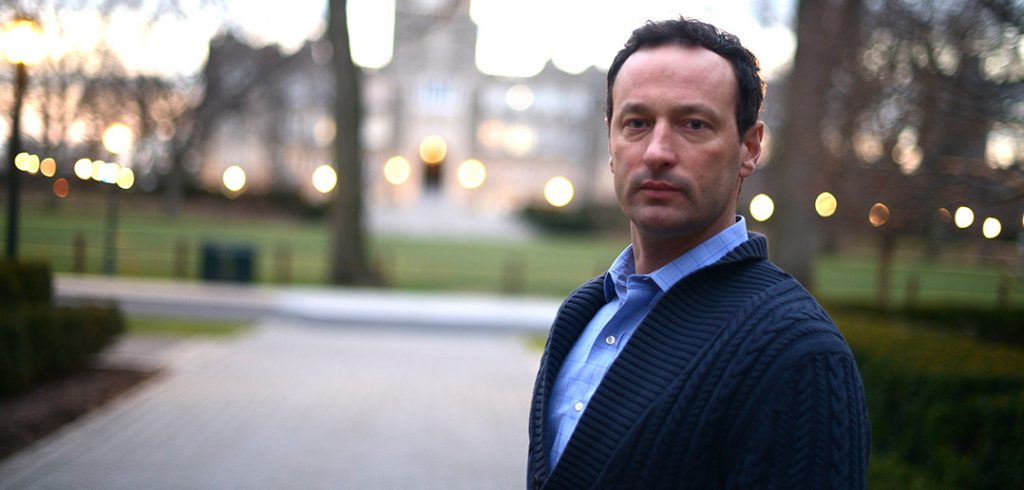 Marc Conte standing on the Rose Hill campus with Keating Hall behind him.