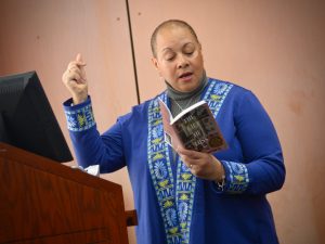 Maria Aponte stands in front of a podium and reads a poem from her second book, "The Gift of Loss."