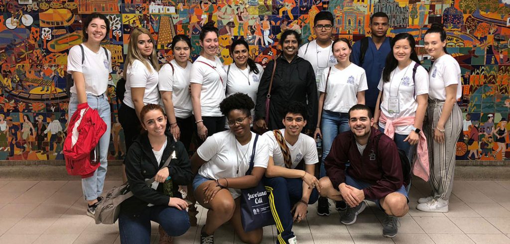 Fordham pre-health students in Cali, Columbia for a service learning trip. They are standing against a colorful mosaic.