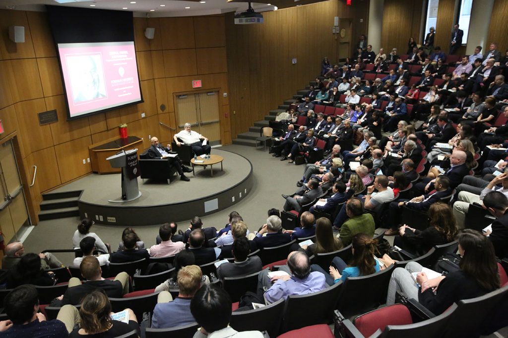 McNally Amphitheatre's seats filled with people listening to Joseph Stiglitz and Bruce Greenwald speak from a stage on the ground floor.