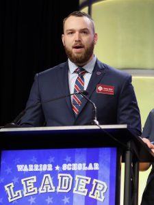 A man wearing a suit and standing in front of a podium that says "Leader"