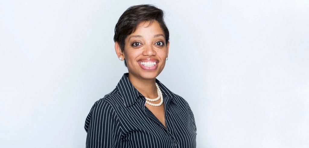 A woman wearing a black and white striped blazer smiling against a white background