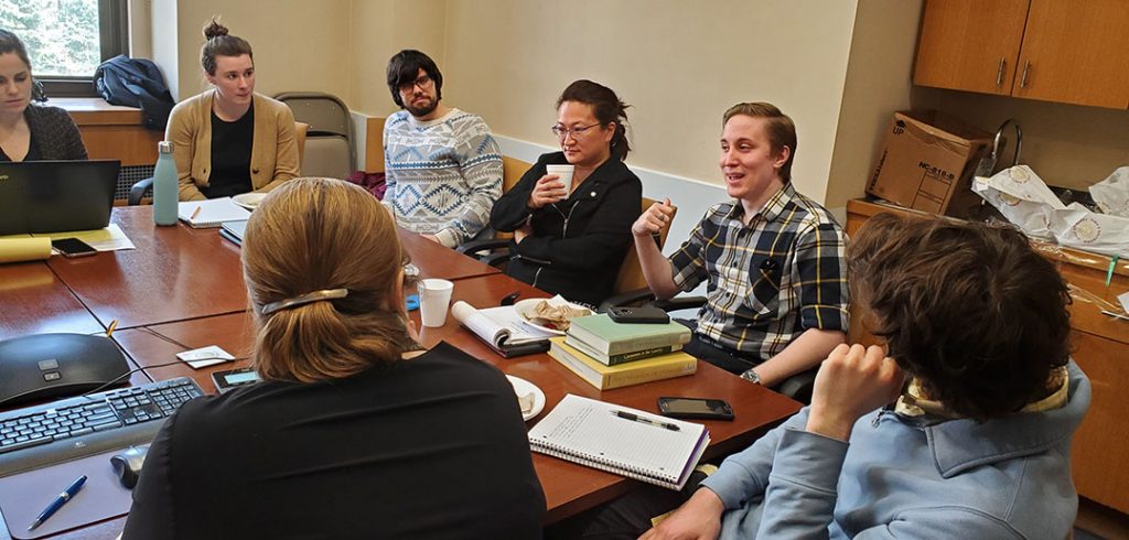 Students sitting around a table talking with faculty