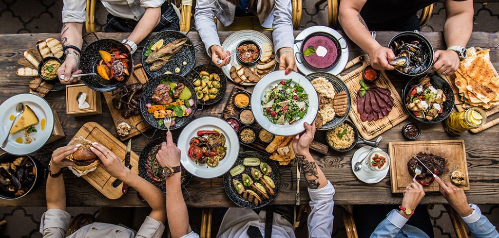 Table set with food and people's hands grabbing for the fare