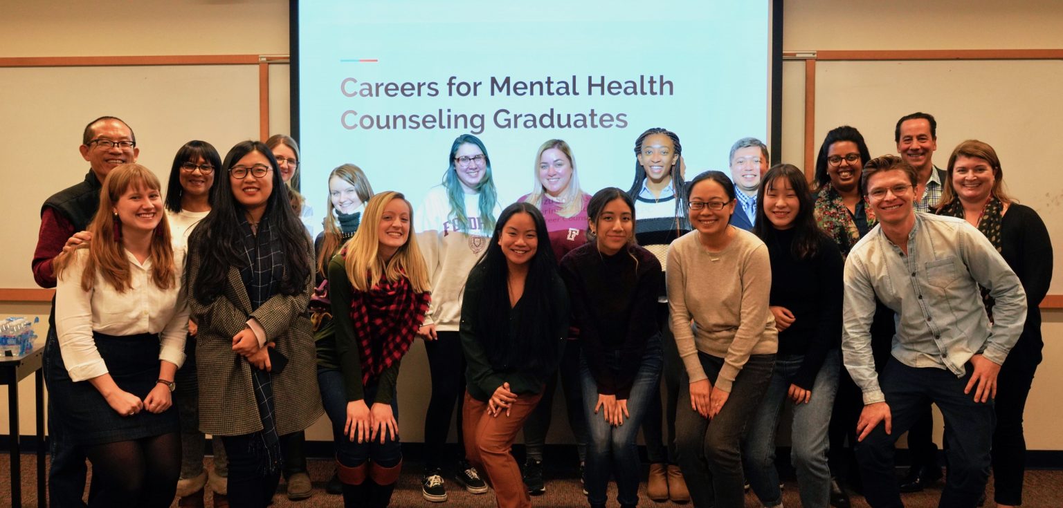 Students, staff, and faculty posing in front of a PowerPoint presentation screen