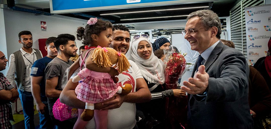 Man holding child, another man greeting them