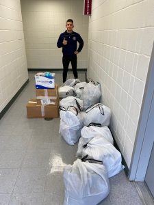 A student stands in front of a row of boxes and bags.