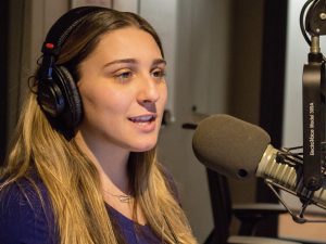 A young woman wearing headphones and speaking into a microphone