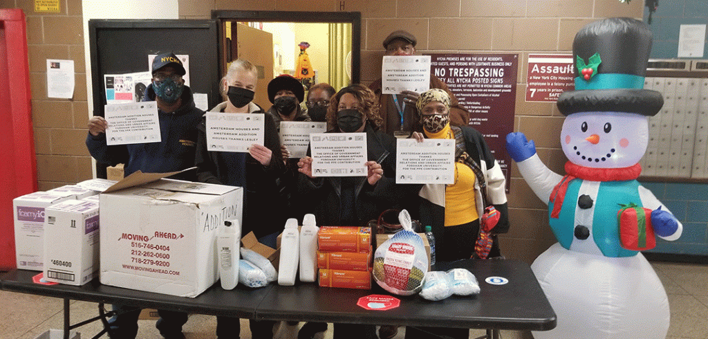 People from the Amsterdam Houses and Amsterdam Addition holding signs of gratitude for Fordham while stanidng in fron tof turkeys and other Thanksgiving supplies