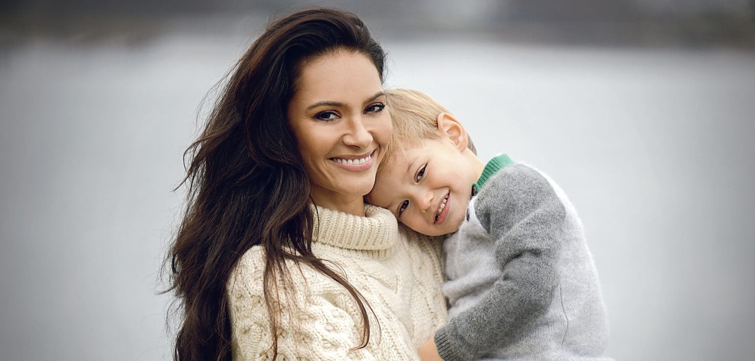 A smiling woman holding a toddler in her arms