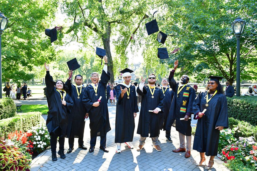 Veteran graduates from the School of Continuing and Professional Studies throwing their caps in the air.