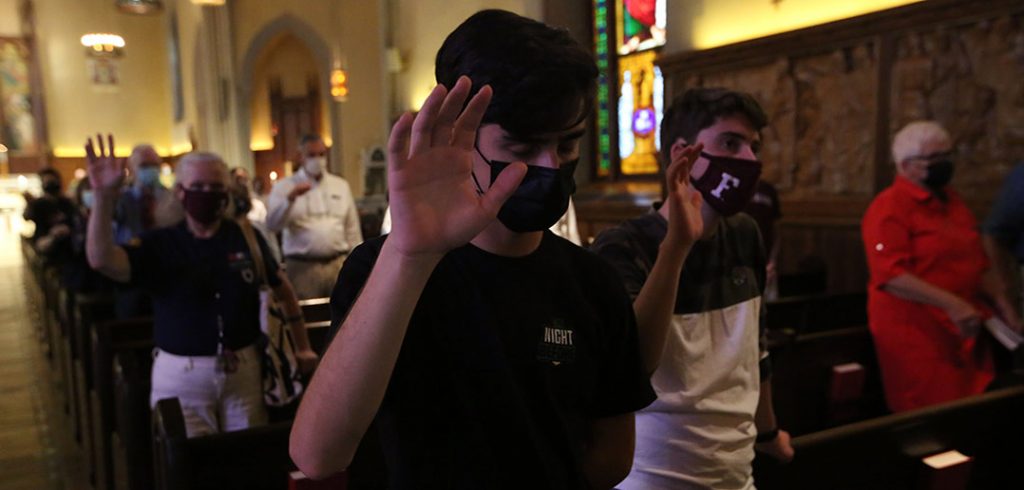 People raising their right hands toward Lower Manhattan during a 9/11 memorial service at the University Church