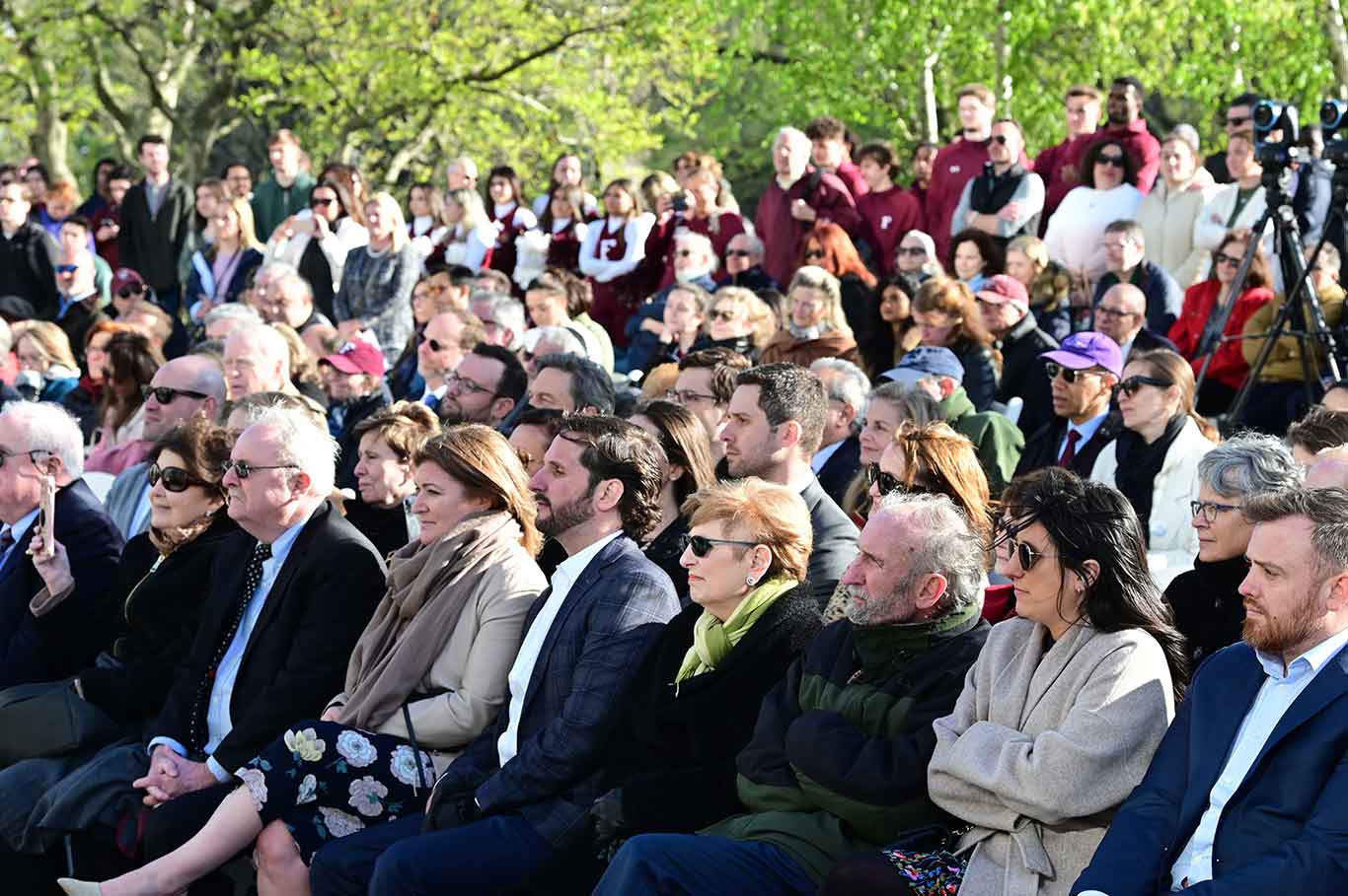 A crowd sits and watches the ribbon cutting