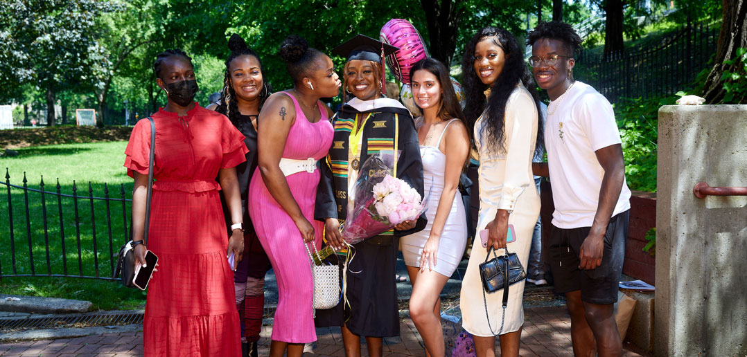 Six people surround a happy graduate and smile.