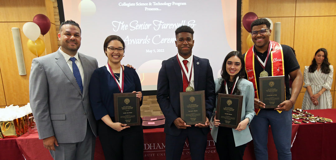 A group of people smile while holding plaques.