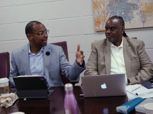 Two seated men in front of laptops