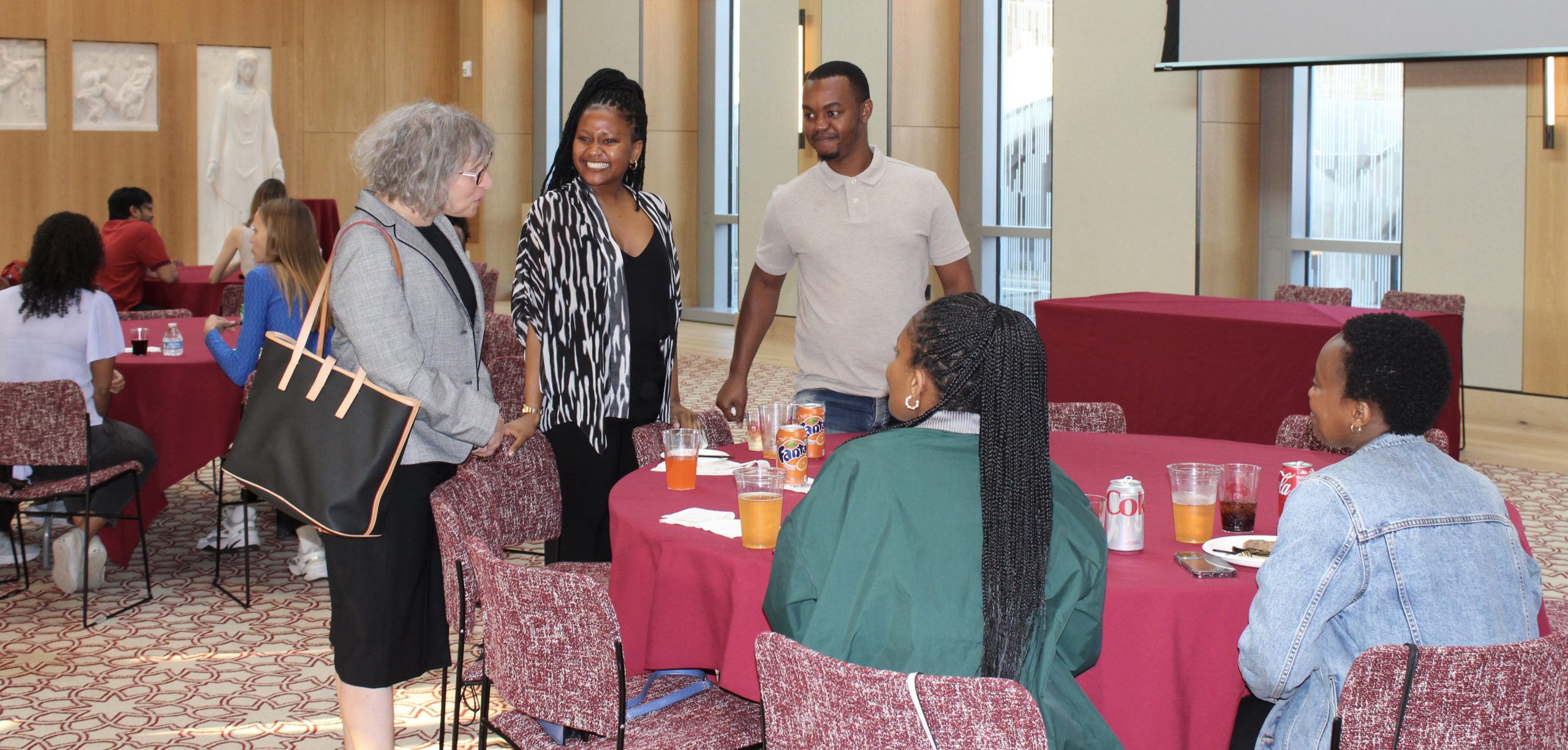 A woman with gray hair speaks with a group of people at a table.