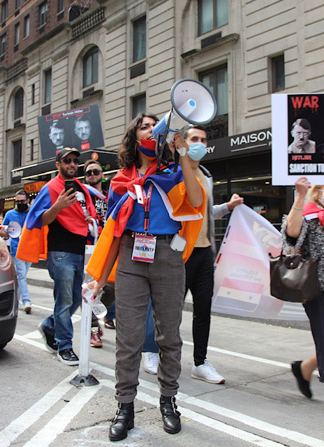 Woman speaking into a megaphone at a protest on the street