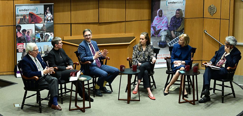 Six panelists sitting together on stage facing each other.