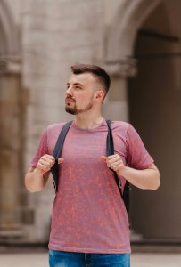 A man wearing a pink t-shirt, facing off to the left