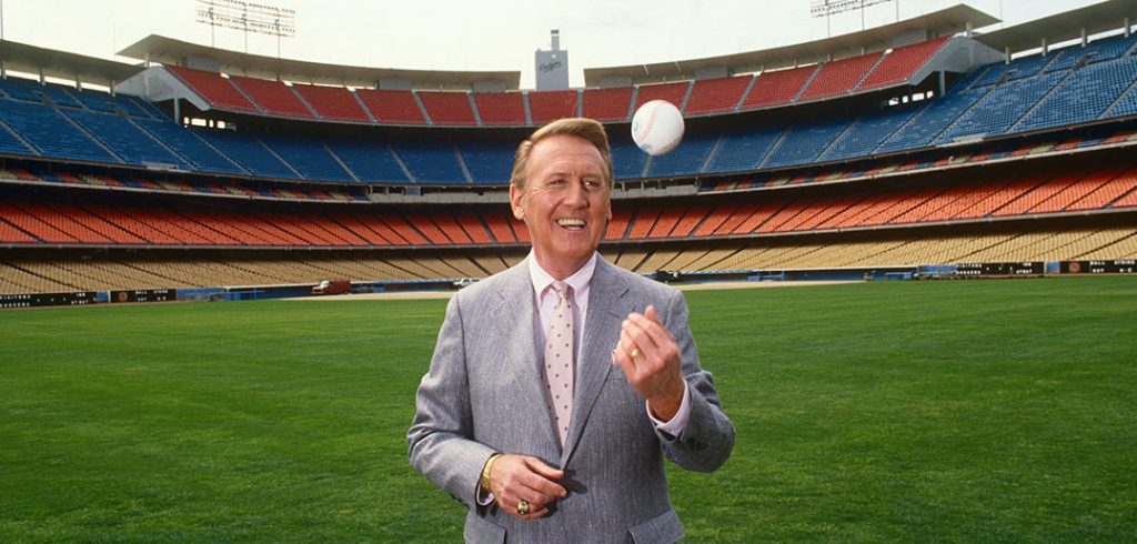 Vin Scully stands in the outfield at Dodgers Stadium in 1987 tossing a baseball into the air