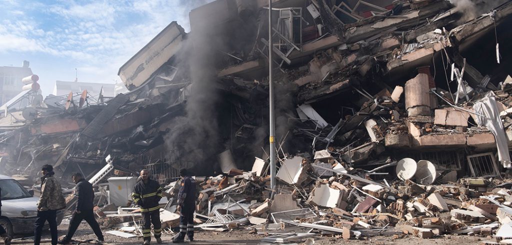 Rescue workers walk past a collapsed building in Turkey