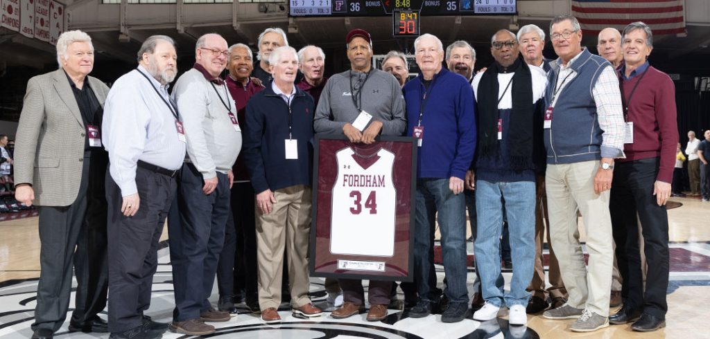 The 1970-1971 Fordham men's basketball team posing at half-court during Charlie Yelverton's jersey retirement ceremony.