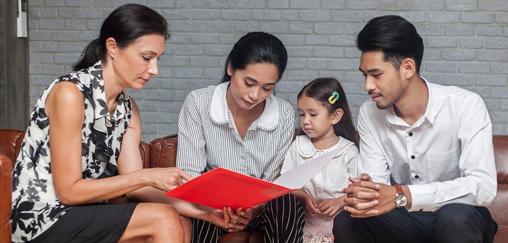 parents and a child look at a piece of paper together with a teacher