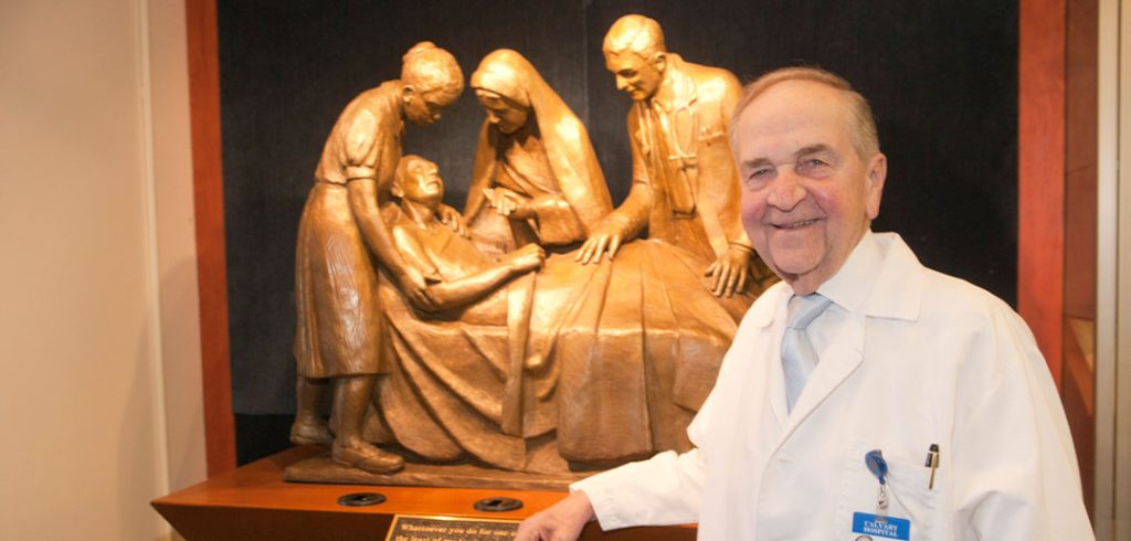 Dr. Michael Brescia poses with a sculpture titled The Compatitor.