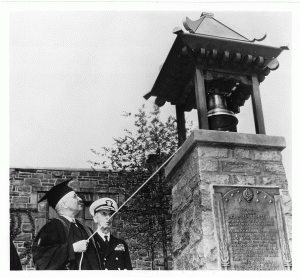 Former President Truman, ringing the liberty bell. There is a man in uniform next to him. 