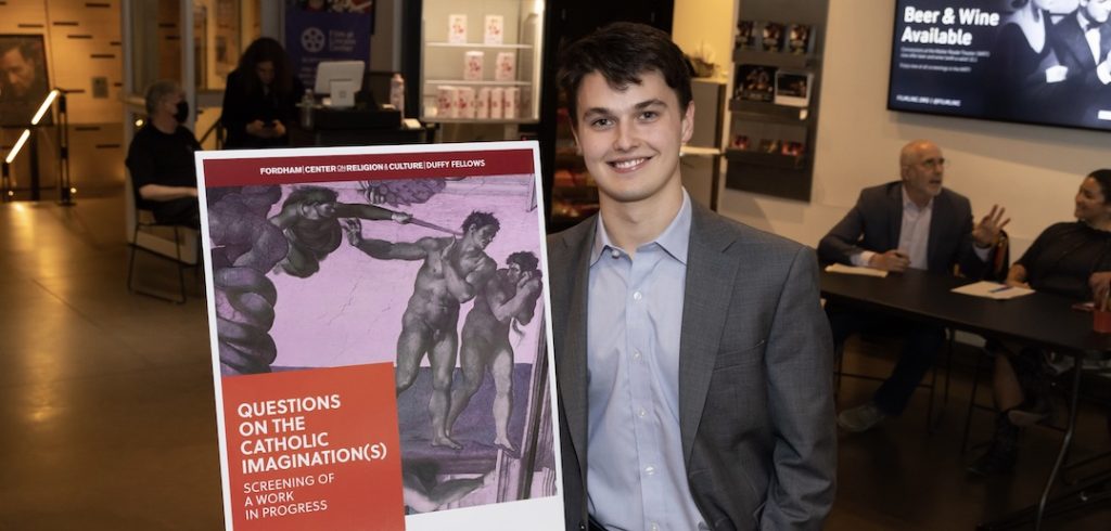 Henry Sullivan smiles besides a poster that advertises a screening of his documentary.