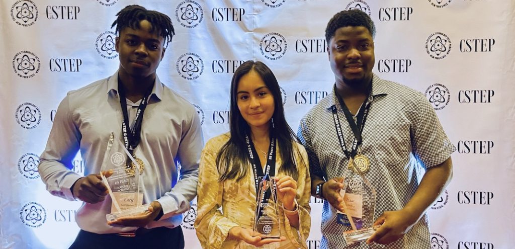 Latif Diaoune, Daphne Buitron, and Isaac Mullings stand and hold awards.