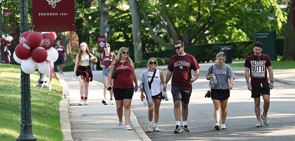 People wearing Fordham T-shirts and walking on the Rose Hill campus during Homecoming weekend in 2022