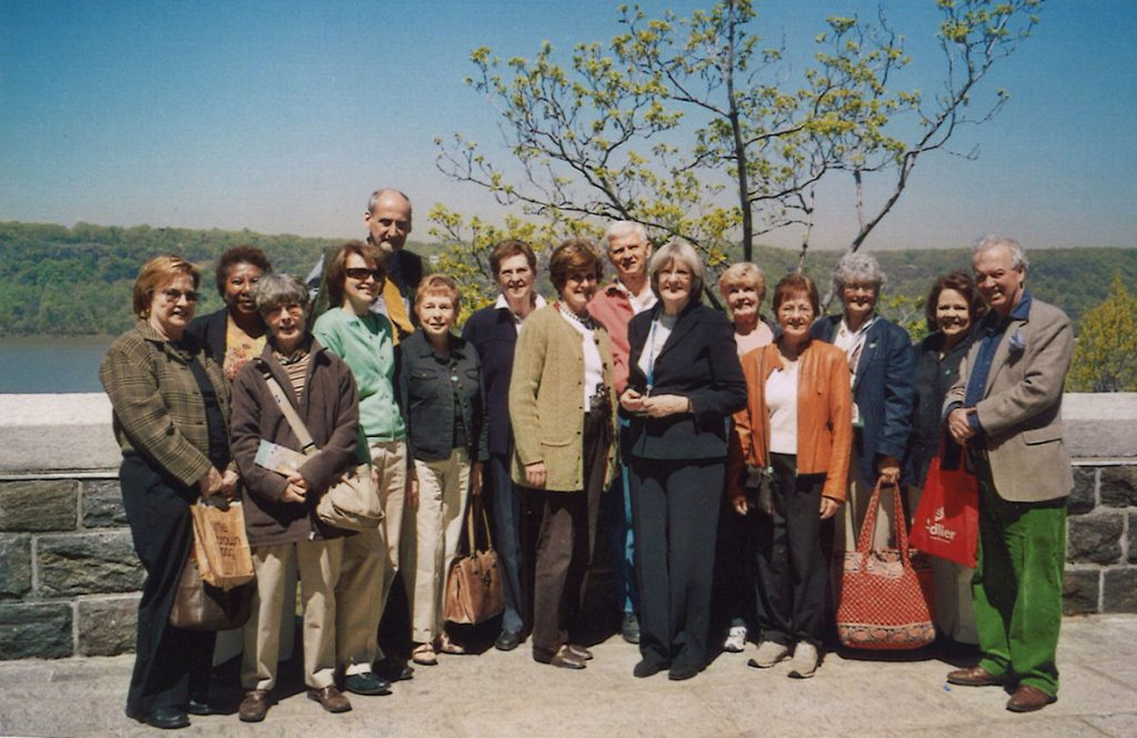 people standing together in a line outside with a river behind them