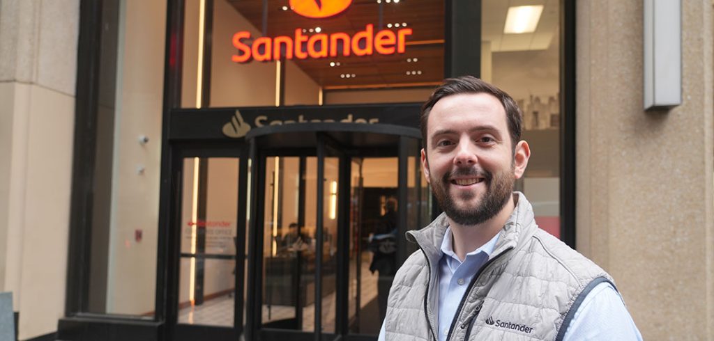 A man standing in front of a bank entrance.