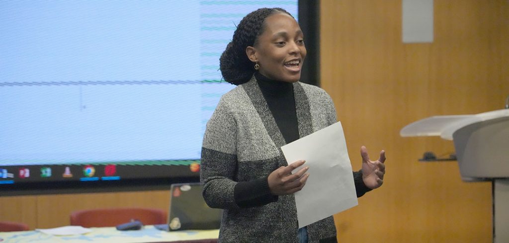 A woman speaks with a piece of paper in her hand.