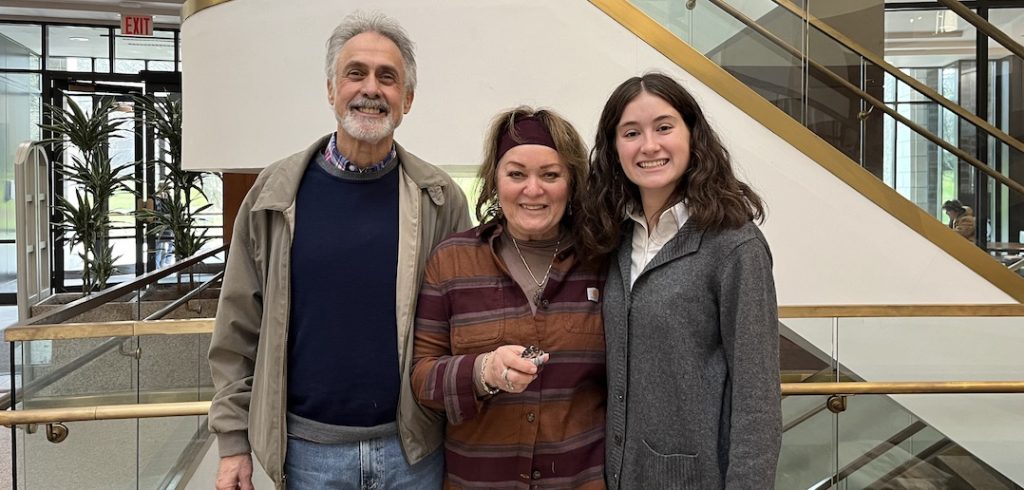 Student Sophia Maier and two guests smile for a group photo in the Walsh Library.