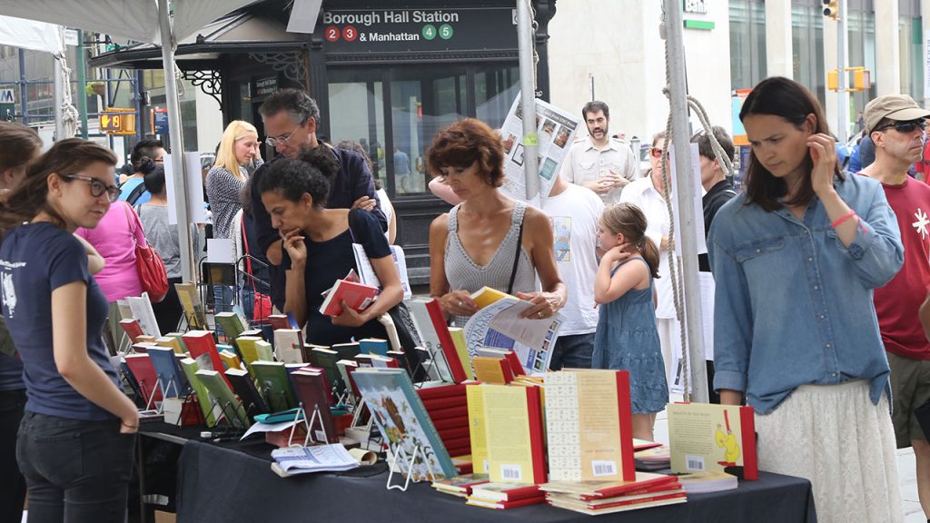 People looking at books on tables outside in NYC