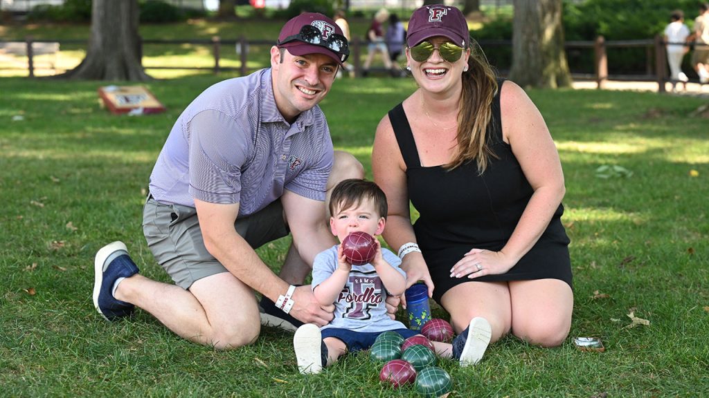 A family poses with their todler, all wearing Fordham gear.