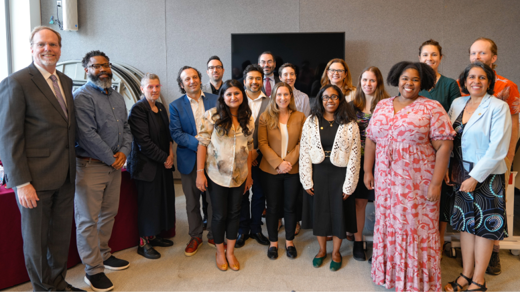 A group of people stand in a semi-circle at a ceremony to celebrate newly tenured and newly promoted faculty and Fordham University