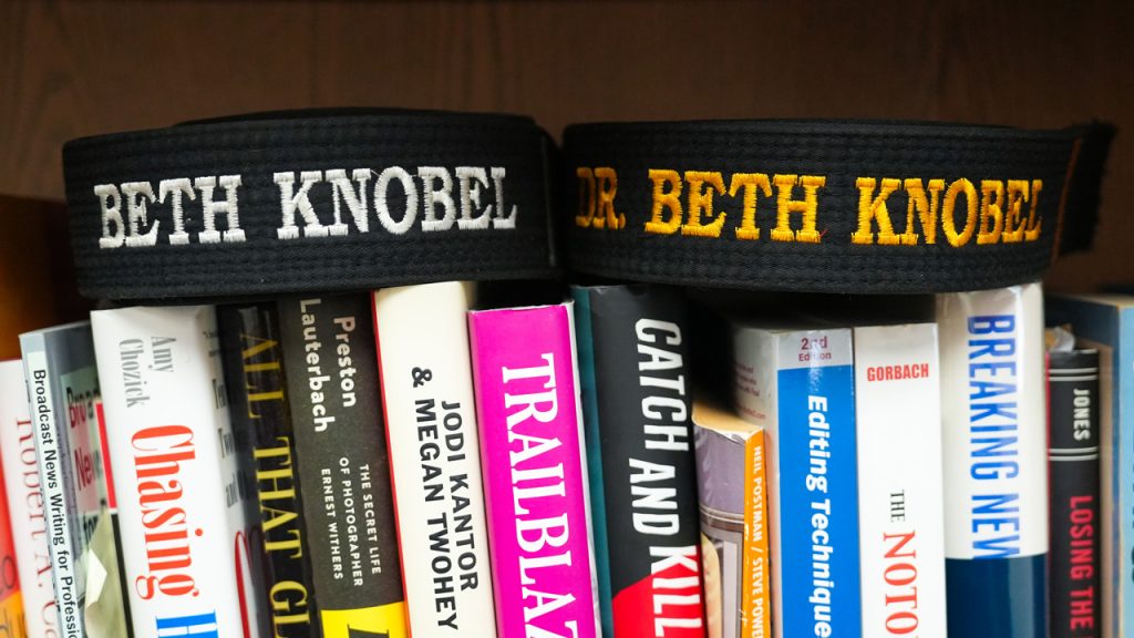 Two black belts that each say "Dr. Beth Knobel" in a bookshelf