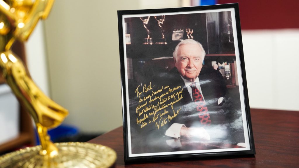 A framed and autographed photo of Walker Cronkite rests on a table.